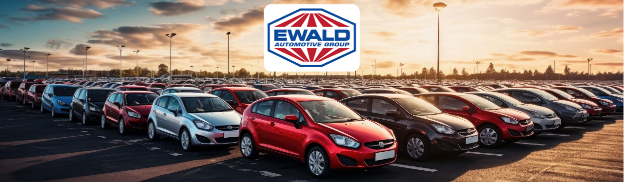 An abundance of vehicles parked on the lot at Ewald Automotive Group with the sun setting overhead